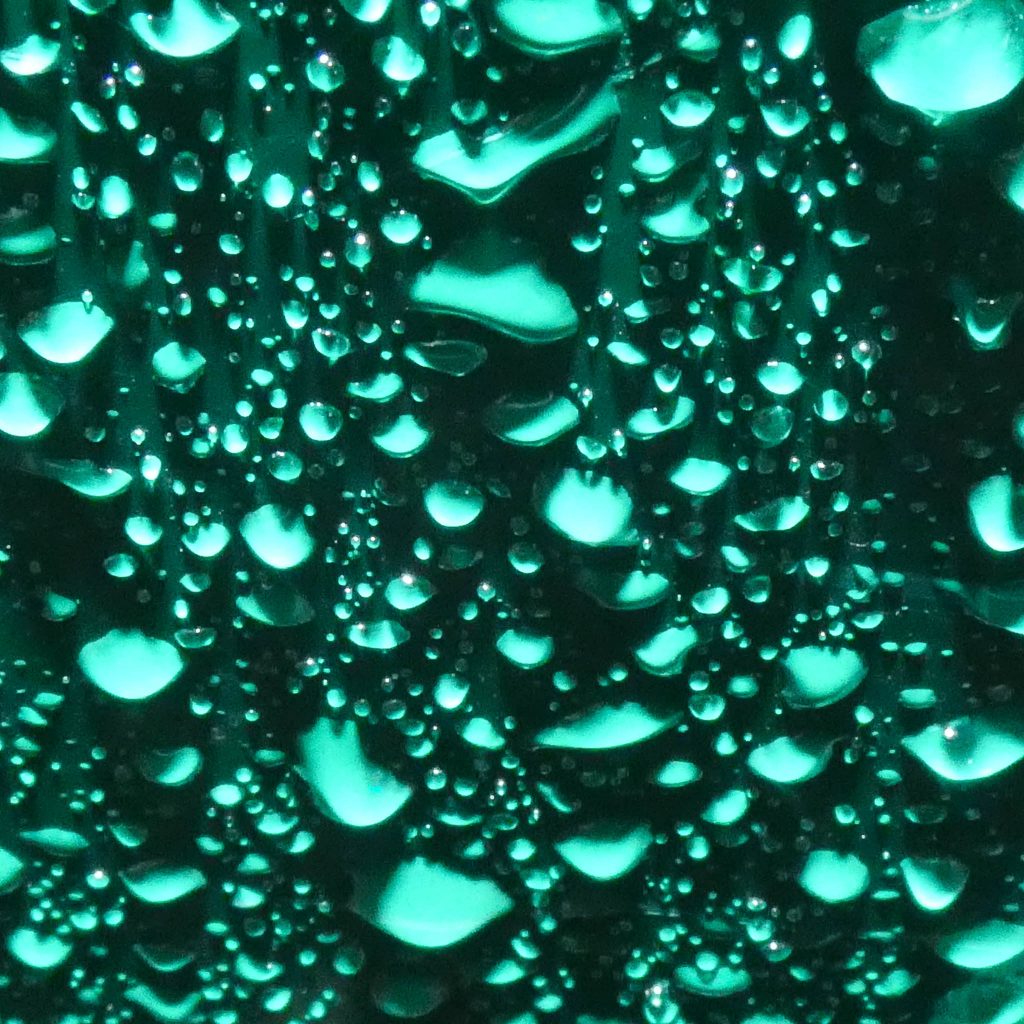 Une photographie Macro de gouttes d'eau sur fond vert.