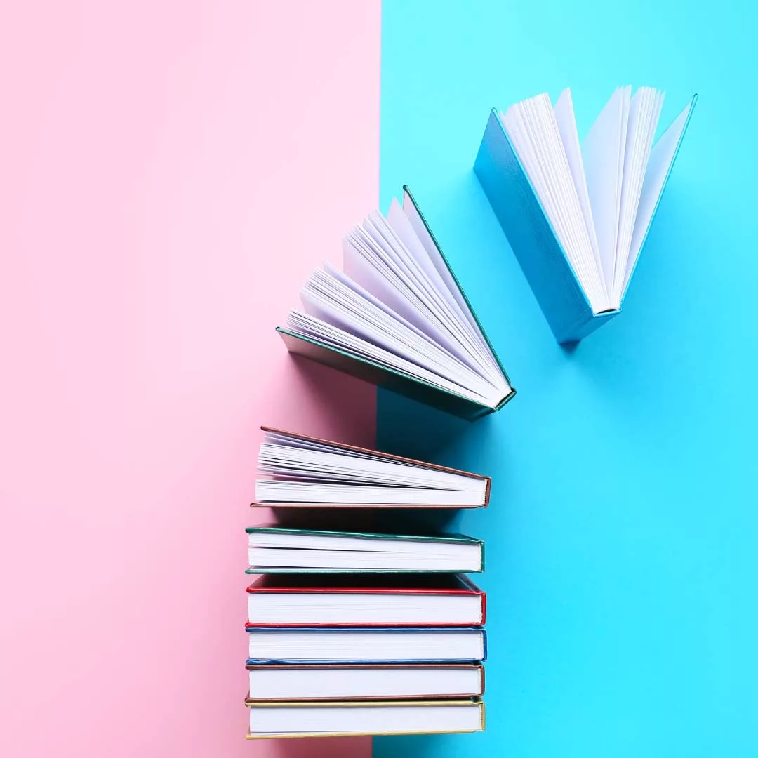 Une pile de livre sur fond rose et bleu, qui représente mes recueils.