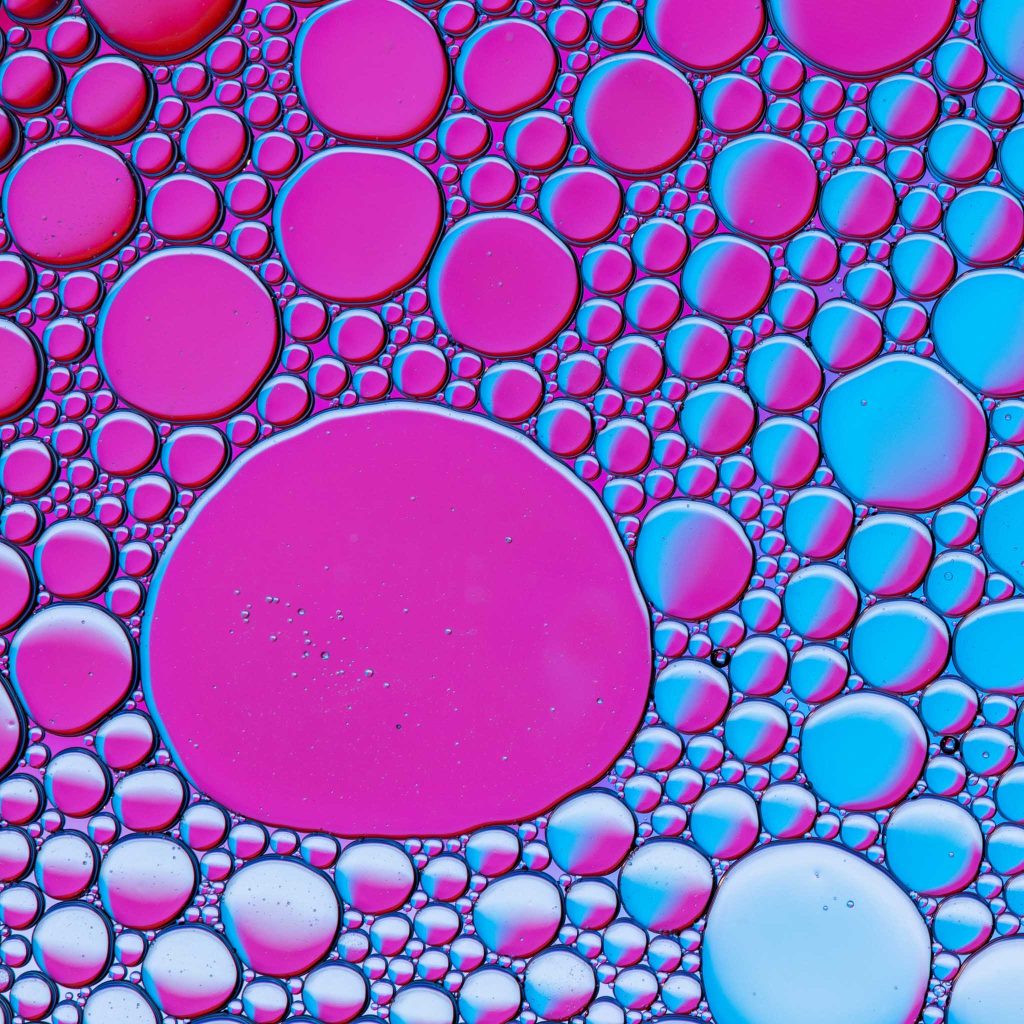 Une photo de bulles colorées (roses et bleues) vues sous un microscope. Illustre l'idée que l'écriture poétique est semblable à une expérience en laboratoire.